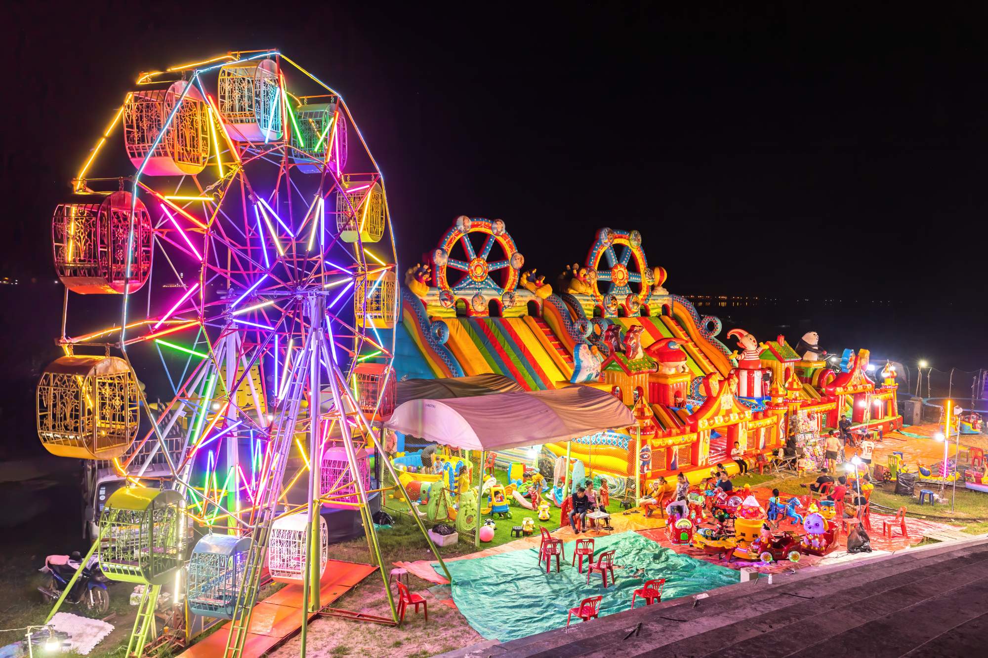Jigsaw Puzzle Illuminated_Ferris_wheel,_bouncing_castle_and_carousel_at_night_in_a_funfair_in
